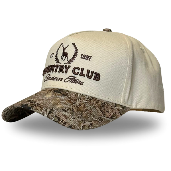A beige two-tone trucker hat with camouflage pattern on the visor and an embroidered logo on the front.