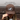 Brown trucker hat with horse logo worn by a person, against a textured brown background.