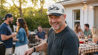 Man wearing a cap with 'The Dad Club Collective' logo at an outdoor gathering.