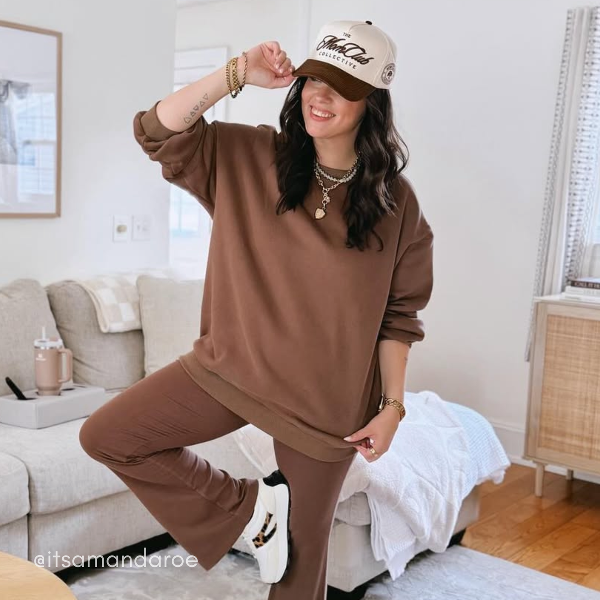 Woman in brown outfit and cap posing in a living room