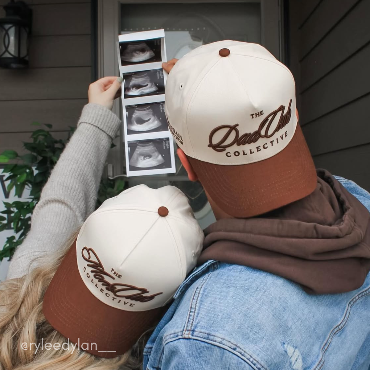 Two people wearing 'The Mom Club Collective' hat and the Dad Club Collective Hat, looking at ultrasound images.