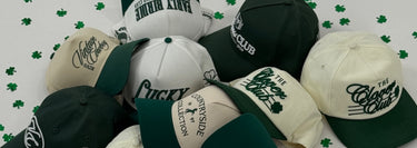 Collection of baseball caps with various logos on a white background with green shamrock patterns.