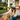 Woman sitting on a porch with a golden retriever wearing a cap with text.